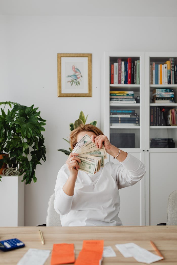 Mastering the First Impression: Your intriguing post title goes here Adult woman conceals face with banknotes in a modern indoor office space.